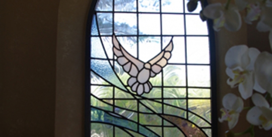 stained glass arched window with modern coloured ribbons and dove
