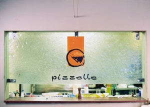 kiln formed clear textured window with orange and black pizzelle logo