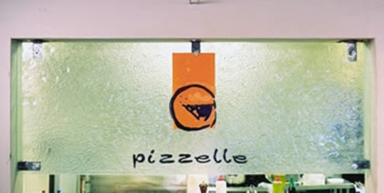 kiln formed clear textured window with orange and black pizzelle logo