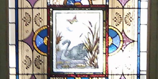 stained glass window with geomatric patterns, painted florals and swan in reeds