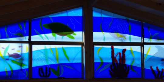 close up of ocean themed fused glass panels in window