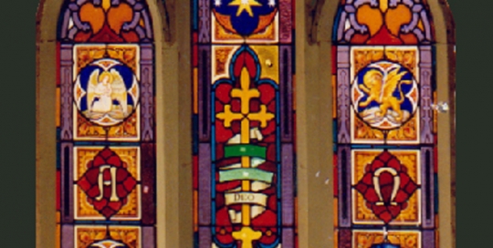 three arched stained glass windows with religious iconography