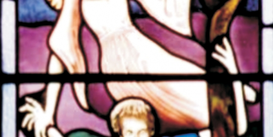 close up of stained glass window of angel holding man on tree