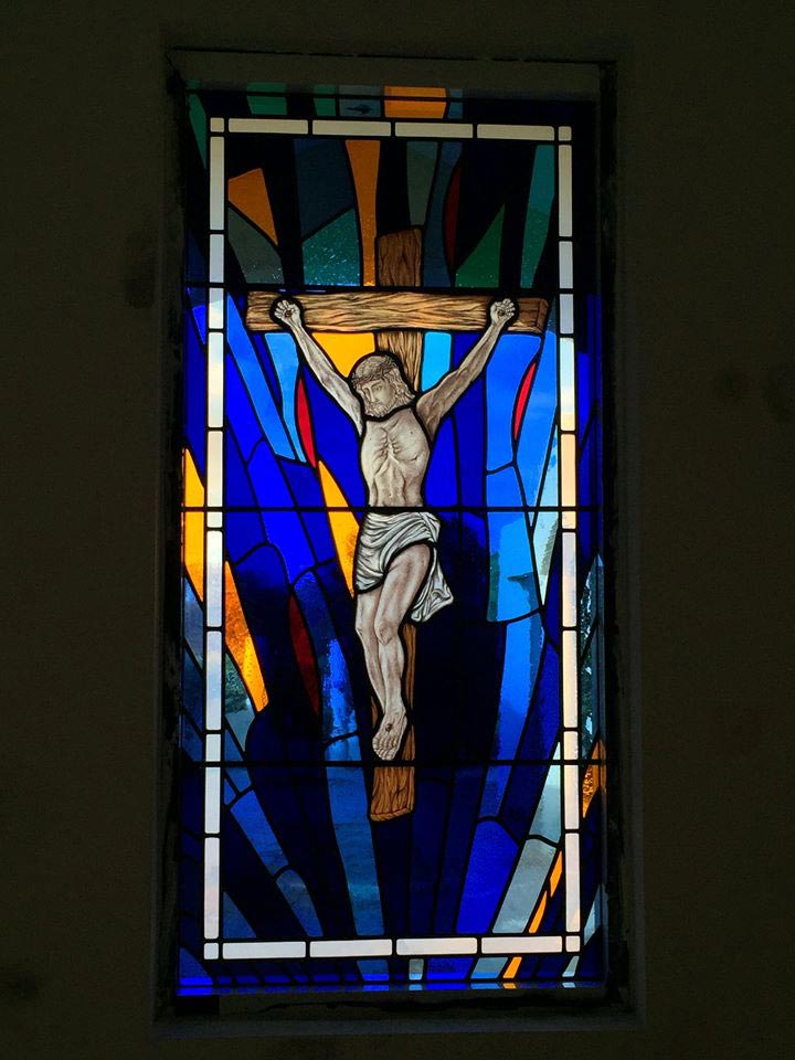 bright stained glass window with painted jesus on the cross