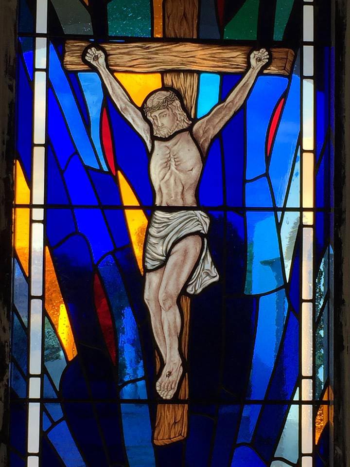 bright stained glass window with painted jesus on the cross