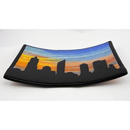 fused glass art piece of silhouette city in front of sunset