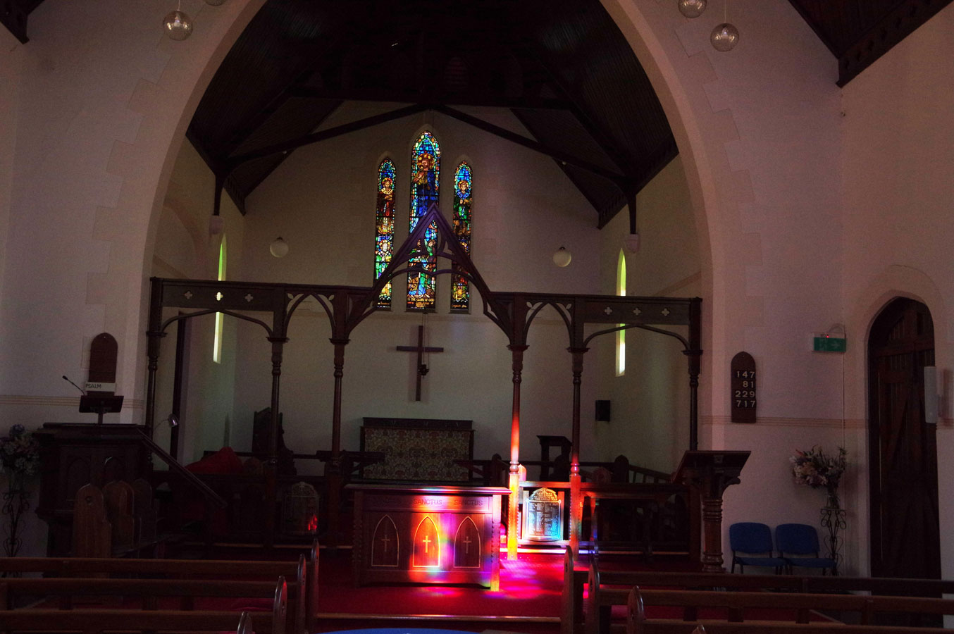 interior of saint james parish in moora showing alter with three traditional stained glass window arches.