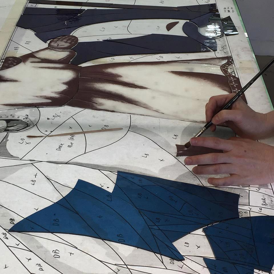 pieces of glass being painted on stained glass design