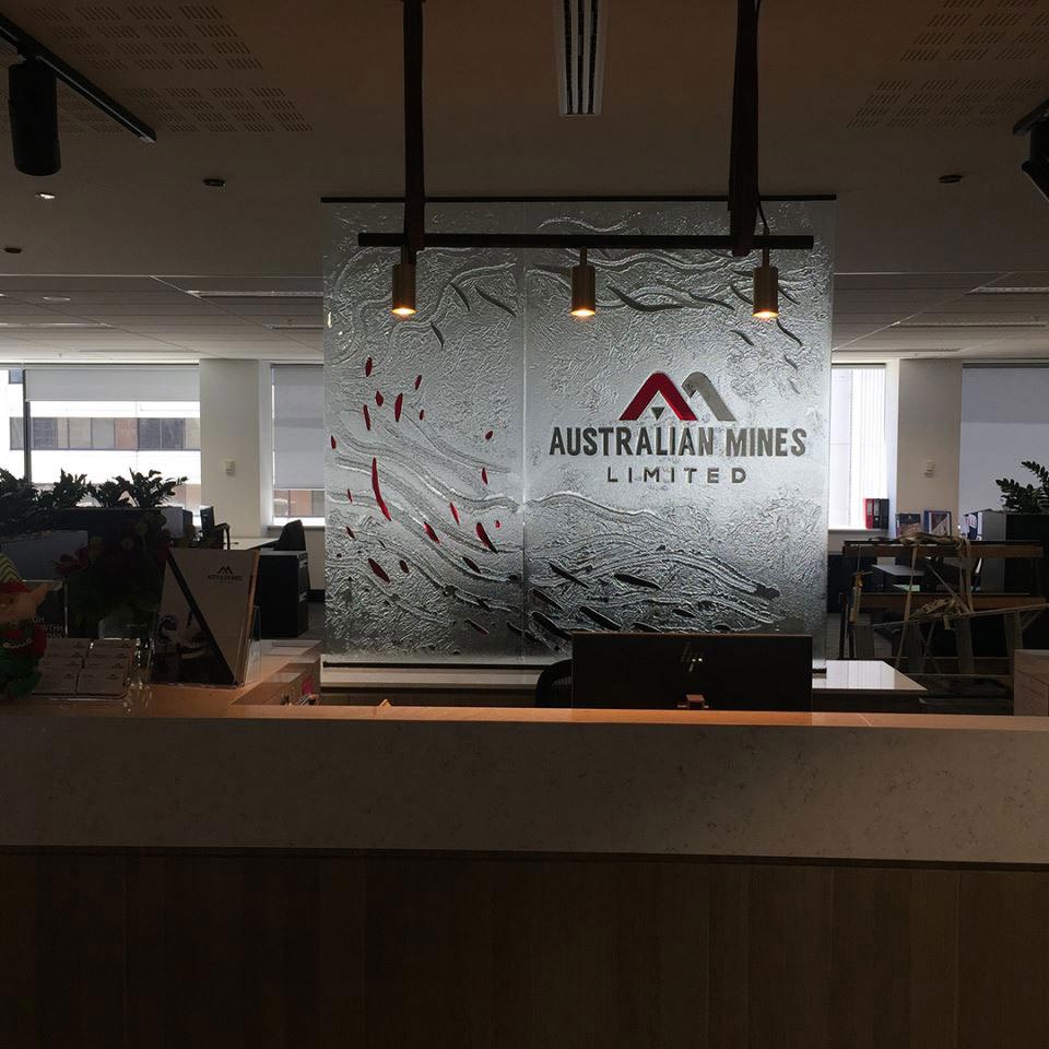 reception desk in front of clear textured kiln formed with logo in laminated coloured glass signage