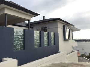 kiln formed wave clear texture glass panels in rendered blue privacy fence showing house and overlooking the river