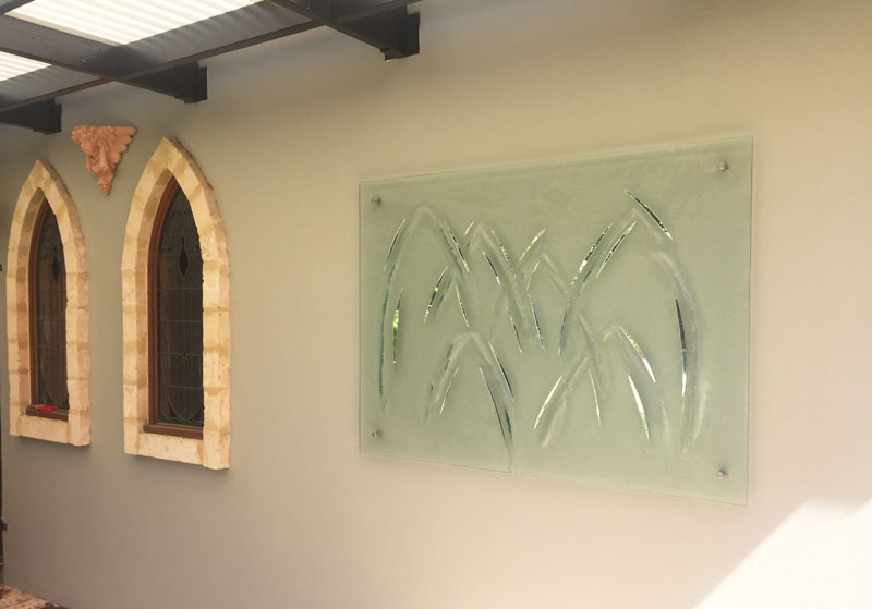 wall with two arch stained glass windows and kiln formed textured glass with mirrored details wall art