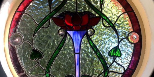 stained glass round window with flower motif in art nouveau design
