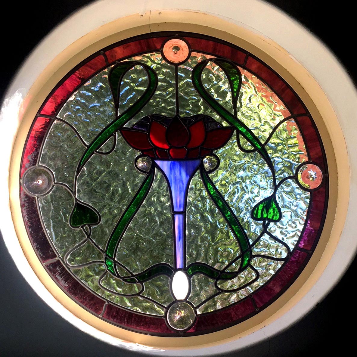 stained glass round window with flower motif in art nouveau design