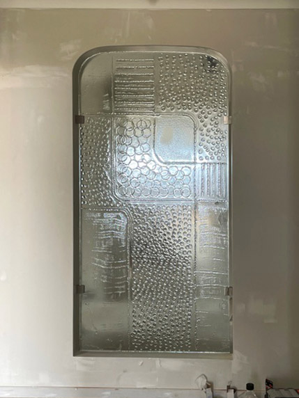 feature slumped glass panel set in unfinished wall