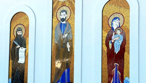 3 mosaic glass panels of religious figures on the exterior of a church