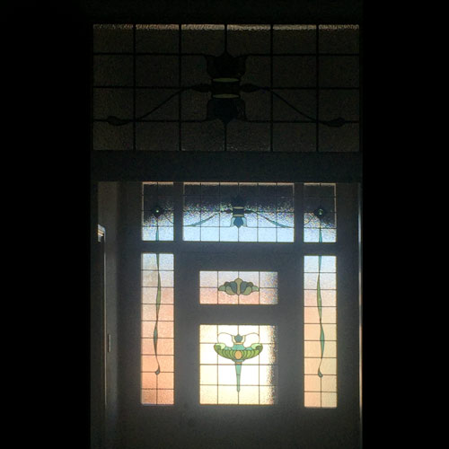 inside of front door showing light through eight stained glass panels in a mostly clear classic style