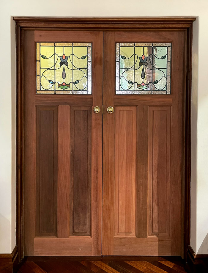 two wooden doors with identical art nouveau stained glass design