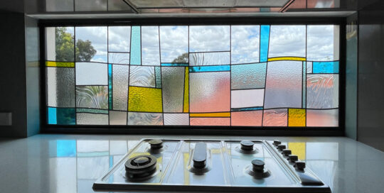 stove with splash back of clear textured blue and yellow stained glass