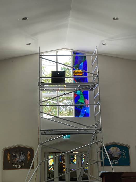 one of three colourful lancet windows installed with scaffolding in front