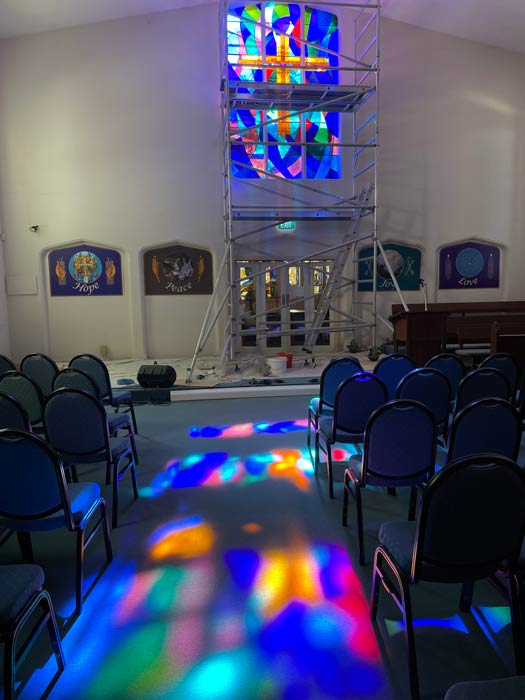 stained glass window in church with light projections down the centre aisle