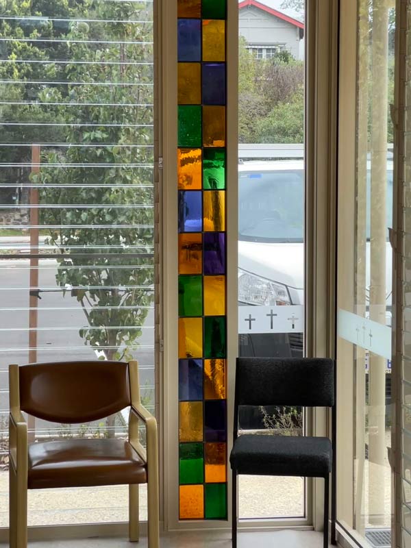 two chairs in front of stained glass lancet window