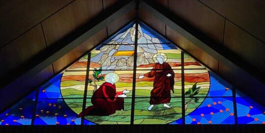 triangular stained glass window of Jesus and disciple in fields