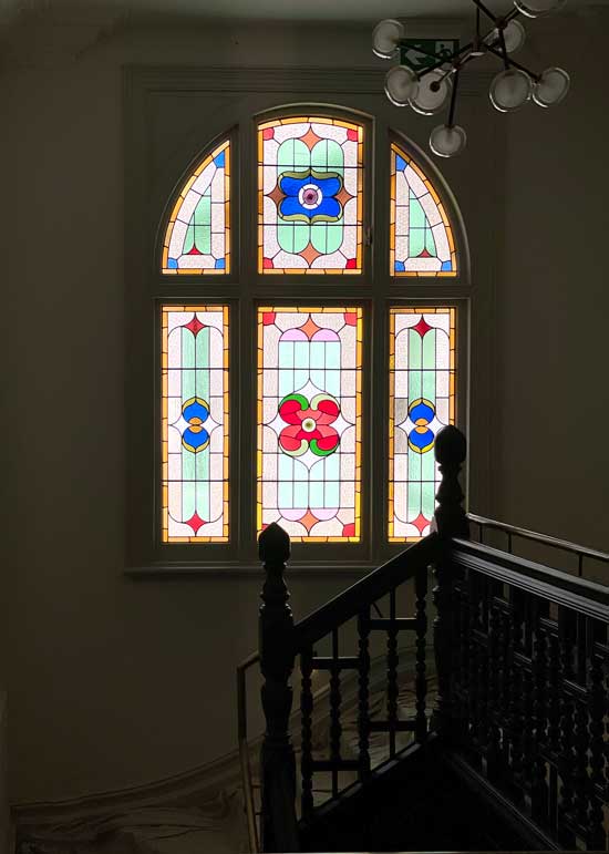 staircase with arch, stained glass window in pastel colours with bright flowers